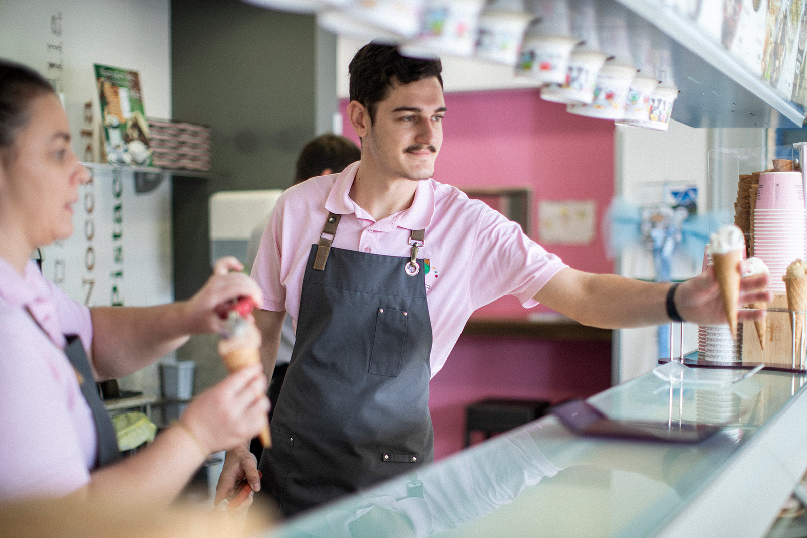 De Zordo Eiscafé Grünstadt Mattia De Zordo reicht Eis in der Waffel über die Eis Theke